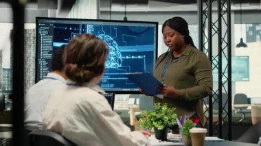 Yatırımcılar, deneyimli bilgisayar bilimcilerinin teknoloji sunumunu dinlemek için başlangıç ofisinde toplanıyorlar. Afrika kökenli Amerikalı kadın ve iş adamları teknoloji ajansının yönetim kurulu toplantısında, kamera B