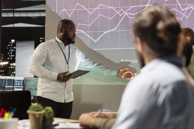 Siyahi iş danışmanı konferans odasında yıllık raporlara ilişkin sermaye fonları ve gelir verilerini sunarak, kar artışı ve yeni proje için bütçe tahsisini gözden geçirdi. Geç saat toplantısından sonra.