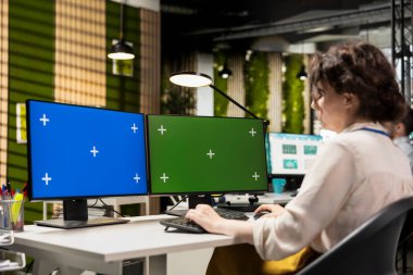 Kadın analist çizelgeleri kroma anahtarıyla analiz etmek, iş yönetimi verimliliğini artırmak ve kalkınma hedeflerine ulaşmak için strateji raporları hazırlamak için bilgisayar monitörleri kullanır..