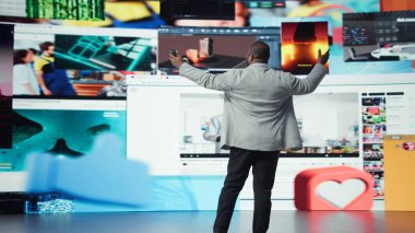 Gülümseyen adam bir tuşa basarak binlerce videoya erişebiliyor. Neşeli Afro-Amerikan erkeği boş zamanlarında akıllı telefondaki favori online videolara göz gezdirmeyi sever. Kamera A