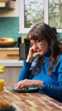 Yaşlı adam sohbete devam ederken dikey videolu olgun eş rahatsız ve ilgisiz hissediyor. Evde emeklilikte monotonluk ve ilişki gerginliğinin yoğun ruh hali altını çiziyor. Kamera B.