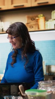 Dikey Video Yaşlı çift evde sabah rutini için sağlıklı bir kahvaltı hazırlıyor. Olgun karı koca gündelik sohbetlerini paylaşıp, evde olumlu anlar yaratıyorlar.