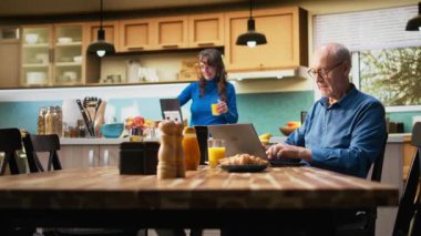 Kıdemli erkek ve kadın zaferi kutluyor. Heyecanlı tebessümlerle tezahürat yapıyor, kahvaltı ve kahve içerken sohbet ediyorlar. Olgun çiftler, emeklilik hedefleri için samimi bir başarı anının tadını çıkarırlar. Kamera A.