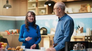 Yaşlı insanların portresi kahve ve neşe dolu gülümsemelerle, ev işlerinden ve sabah rutin anlarından zevk alarak evde duruyor. Huzurlu bir yaşam tarzı, doğal ve tatmin edici bir yaşam. Kamera B.