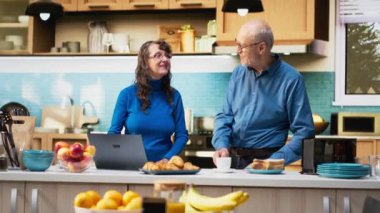 Yıllanmış karı koca evlerinin mutfağında dizüstü bilgisayar uygulamalarına göz atıyorlar, kahve ve huzur içinde dinlenmenin tadını çıkarıyorlar. Neşeli bir yaşam tarzı, mutlu bir yaşam ve emeklilikte rahat anlar. Kamera B.