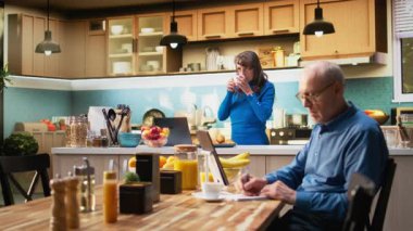 Mutfakta yaşlanmış bir insan ev hayatından keyif alıyor, kahve ve yemekle tezgahın yanında gülümsüyor. Huzurlu emeklilik ve refahın huzurlu yaşam tarzını yansıtan emekliler. Kamera A.