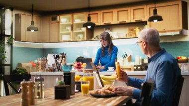 Yetişkinlerin akıllı telefonlarıyla internete bakması, mutfakta gülümsemesi, kahveyle rahatlaması ve huzurlu emeklilik hayatının tadını çıkarması. Emeklilik, pozitif yaşam tarzı ve doğal ev hayatı. Kamera A.