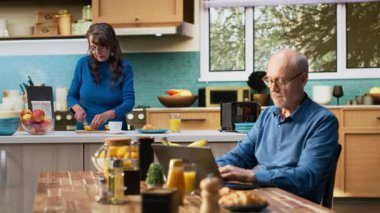 Olgun yaşlı bir adam, sakin bir mutfak anındaki dizüstü bilgisayarında kahve fincanıyla internete girip emeklilikteki rahat yaşam tarzını ön plana çıkarıyor. Huzurlu bir hayat ve ev hayatı. Kamera B.