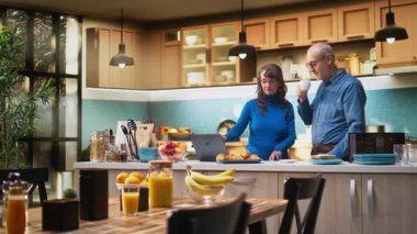Yaşlı evli çiftler ev mutfağında dizüstü bilgisayarlarında geziniyor, bir fincan kahve ve huzurlu rahatlığın keyfini çıkarıyorlar. Neşeli bir yaşam tarzı, mutlu bir yaşam ve emeklilikte rahat anlar. Kamera A.