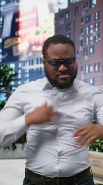 Dikey Video Siyah Adam, modern yaşam tarzı ve kültürel çeşitlilik için şehir merkezindeki kaldırımda dans ediyor. Mimari ve dinamik funky kişilikli eğlenceli metropol atmosferi.