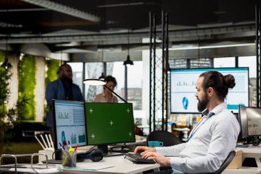 Kurumsal analist, ilerleme ve verimlilik elde etmek için bilgi grafiklerini analiz ederek, bilgisayarın yanındaki durumu izliyor. Veri yönetimine odaklanan erkek çalışan.