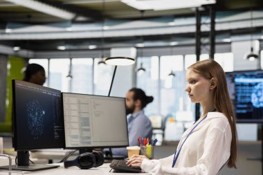 Kadın teknisyen AI LLM sohbet robotuna sistem performansını artırmak için danışmanlık yapıyor. Teknik başlangıç çalışanı staj yapıyor. El görevlerini otomatik hale getirmek için yapay zeka asistanına güveniyor.