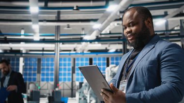 Siyah endüstri uzmanı yenilenebilir enerji başarısını sürdürmek için yenilik ve verimlilik sağlayan bir güneş teknolojisi tesisinde üretim verilerini inceliyor. Çevre dostu sürdürülebilir çözümler. Kamera A.