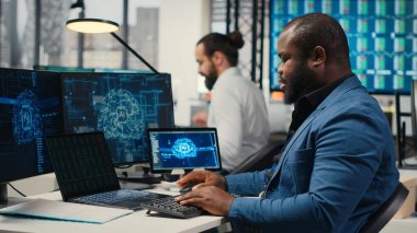 Uzman danışman bilgisayardaki yapay zeka araçlarıyla KPI raporlarını inceleyerek, makine öğrenimi için yapay zeka ağlarıyla çalışıyor. Yenilik ve optimizasyon vurgulanıyor. Kamera B.