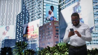 Afrika kökenli Amerikalı erkek, şehir merkezinde yürürken telefonla navigasyon açıyor. Sıradan bir güven, sokak stili ve metropolitan alanının mimarisi aracılığıyla hareketli bir tavırla. Kamera A.
