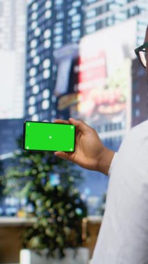 Şehir merkezindeki kaldırımda yetişkin bir erkekle dikey video görüntüleme ekranı modayı, canlı kültürü ve aktif şehir manzarasının enerjisini ön plana çıkaran samimi bir hareketle görüntülendi.