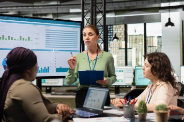 Çeşitli kadın profesyoneller bir toplantıda rapor yazma ve analitik üzerinde dururlar, rekabetçi bir çalışma ortamında başarı hedefleri ve kararlılığı yoluyla güçlendirme gösterirler.