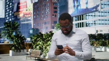 Yetişkin bir adam telefon GPS 'inde yol tarifi arıyor ve şehir kaldırımlarında yürüyor, modern tarz ve şehir hayatı anlayışı. Siyah insan akıllı telefon uygulamalarını ve şehirciliğini kontrol ediyor. Kamera A.