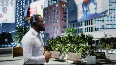 Kendine güvenen, havalı şarkılarda dans eden, modern bir şehir caddesinde yürüyen ve kulaklıkla müziğin tadını çıkaran bir zenci. Canlı metropoliten manzara, şehircilik gibi. Kamera A.