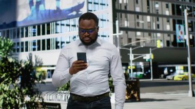 Şehir merkezinde yürümek için internet haritası olan zenci bir adam, şehir merkezindeki gökdelenlere ve titreşimli titreşimlere hayran. Şehir Bulvarı 'nda sıradan bir sokak tarzı. Kamera B.