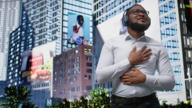 En sevdiği müzikle şarkı söyleyip dans eden modaya uygun Afrika kökenli Amerikalı bir adam sokakta kulaklıkla harika dans hareketleri yapıyor. Kendine güvenen sokak tarzı ve şehir hayatının akışı. Kamera A.