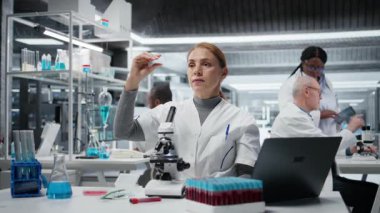 Malzeme bilimci, ince cam kaydırağında yapısal bozukluklar ya da safsızlıklar olup olmadığını araştırıyor. Bileşik mikroskop ve kamera A kullanarak görsel kalite kontrolü yapan bir araştırmacı.