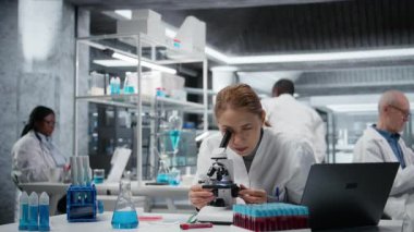 Hücresel analiz için bilimsel mikroskop kullandıktan sonra yorgun biyologlar tıp laboratuarında geriliyor. Yorgun bilim adamı çalışma masasında dinleniyor, optik cihaz teçhizatı ve kamera A ile numuneleri inceliyor.