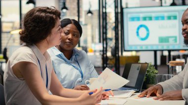 İşe alım ekibi ve bir iş ofisinde özgeçmiş değerlendirmesi yapan bir başvuru sahibi, kariyer deneyimi ve büyüme hedefleri hakkında tartışmalar. Profesyonel işgücü için röportaj süreci.