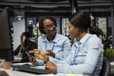 İki kadın gece geç saatlerde ofiste verimliliği ve içgörüyü izliyor, ayrıntılı performans ölçümleri için analitiklerden faydalanıyor ve şirket yönetimini güvence altına almak için bir projeksiyon yapıyor..