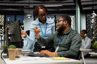 Afrika kökenli Amerikalı işçiler geceleri görev çözmede birbirlerine danışırlar, aylık raporları tamamlarlar ve verimlilik için KPI verilerini incelerler. Başarı için işbirliği.