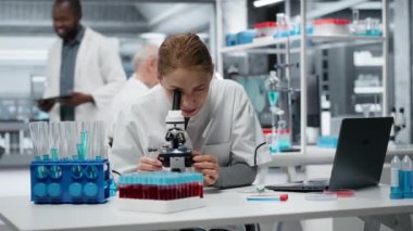 Klinik mikrobiyolog detaylı hücresel analiz araştırmaları için bileşik mikroskop kullanıyor. Kadın sitoteknoloji uzmanı modern laboratuvar tesisinde doku örneği incelemesi yapıyor. Kamera B.