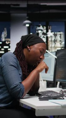 Dikey video yorgun programcı makine öğrenme algoritmalarını analiz ederken ofiste uyuyakalıyor. Uykulu bilişim uzmanı gece geç saatlerde yapay zekanın doğruluğunu geliştirmek için kod mantığını gözden geçiriyor.