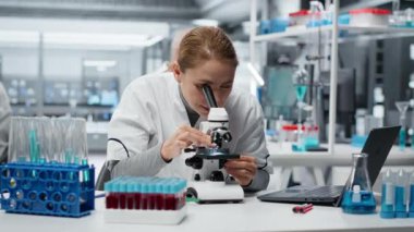 Patoloji slaytlarını inceleyen tarih teknisyeni araştırma merkezinde mikroskop altında. Tıbbi yenilikleri araştıran kadın araştırmacı kendini adamış hücresel analiz çalışmaları, kamera B