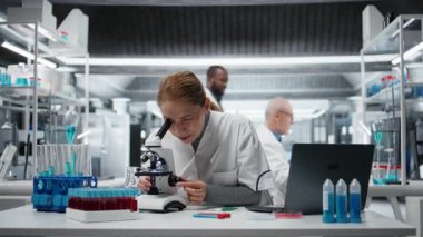 Patoloji slaytlarını inceleyen gülümseyen bilim adamının portresi araştırma merkezinde mikroskop altında. Hücresel analiz çalışmaları ve kamera A ile tıbbi yenilikler yapan mutlu kadın.