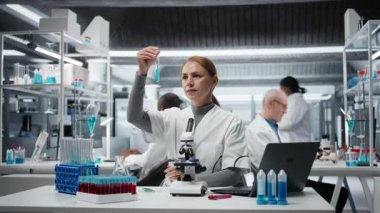 Laboratuvardaki bilim adamları analiz etmek için mavi sıvıyı test tüpüne koyuyorlar. Laboratuvar çalışanı spektroskopik analize hazırlanmak için kimyasal örnek transfer ediyor. Kamera A.