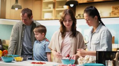 Ebeveynler çocuklarına lezzetli ev yapımı pizza yapmayı öğretiyor. Genç kız ve küçük oğlan birlikte yemek yapmayı öğreniyorlar. Hafta sonu aktiviteleri sırasında aile zamanı. Kamera B.