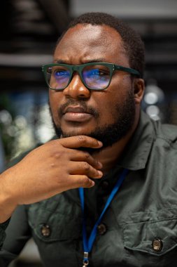 Siyah genel müdür rasyonel bir çözüm öngörüyor ve çenesini kaşıyor. Mesai saatlerinden sonra masa başında çalışıyor. Adam eleştirel düşüncelere dalıyor, her seçeneği farklı bir bakış açısıyla değerlendiriyor..