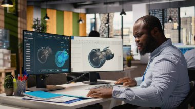 Bilgisayar üzerinde karbon ayak izini azaltmak için rüzgar türbini tasarımını optimize etmek için CAD programı kullanan teknisyen. Ar-Ge çalışanı gelişmiş malzemeleri çevre dostu yel değirmeni bileşenleri için test ediyor, kamera A