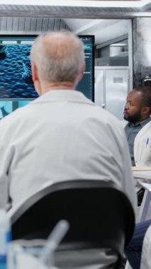 Dikey video tıp fakültesi profesörü moleküler biyoloji kavramları hakkında araştırmacılara danışmanlık yapıyor. Laboratuardaki kadın DNA organizma yapısını öğrencilere açıklamak için ekranı kullanıyor, B kamerası.