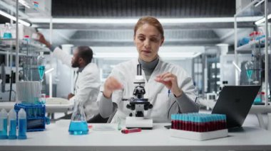 Klinik teknisyeni hasta biyopsi slaytını inceleyerek anormal hücresel büyümeyi tespit ediyor. Teşhis doğrulaması için hastane laboratuvarında yüksek teknolojili mikroskop kullanan kadın. Kamera A.