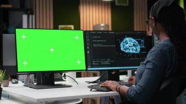 Yapay zeka kullanarak gece geç saatlerde ofisteki yazılımı optimize eden teknoloji ajansı tarafından kullanılan yeşil ekran modeli bilgisayar. Hata ayıklamak için krom anahtar bilgisayarında derin öğrenim kullanan bilişim uzmanı, kamera B