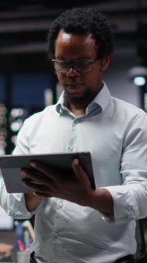 Ofisteki gülümseyen mühendisin dikey video portresi yapay zeka sistemindeki hataları düzeltmeye çalışıyor. Teknoloji ajansının işyerindeki sinirsel ağ hatalarını görüntüleyen mutlu bilişim işçisi, kamera B