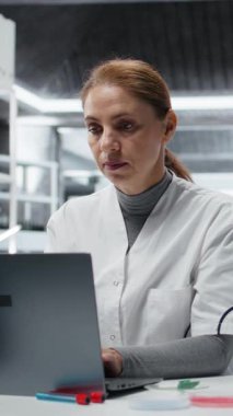 Dikey video gerilim nanoteknoloji araştırmacısı laboratuvarda kafa basıncını hissediyor, dizüstü bilgisayar yazılımı kullanıyor, sürücü tedavisi keşfi yapıyor. Migreni olan laboratuar teknisyeni biyoenformatik uygulama kullanıyor