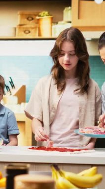 Pizza günü ebeveynler ve çocuklarla mutfakta dikey video aile zamanı mozzarella ve pepperoni gibi malzemeler ekleniyor. Eğlenceli ve lezzetli ev yemekleri, kahkahalarla çevrili. Kamera B.