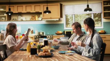 Tablette gülümseyen baba küçük kızıyla sohbet ediyor, ailesiyle kahvaltı yapıyor ve mutfakta güzel ev yemekleri yiyor. Beraberlik ve neşe. Kamera A.