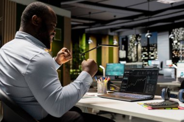 Küresel piyasa trendlerinin yükselişini kutlayan memnun siyah adam, kripto para biriminin başarısı ve para kazanmasıyla mutlu ve neşeli hissediyor. İş geliştirme hedefleri.