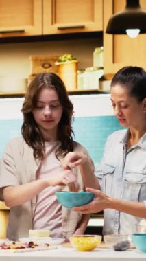 Dikey Video Ebeveynleri ve ergen mozzarella serpiştirme ve ev yapımı pizza hamurunun üzerine rendelenmiş peynir serpiştirme, mutluluk ve mutfak yaratıcılığıyla dolu bir aile anında mutfakta birlikte gülme. Kamera B.