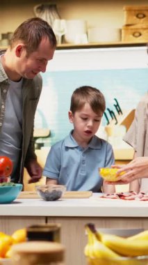 Dikey Video Ailesi mutfakta pizza gününün tadını çıkarıyor ve ev yapımı pizza hazırlıyor. Ebeveynler ve çocuklar lezzetli bir yemekle birlikte kahkaha ve kaliteli vakit geçiriyorlar. Kamera B.