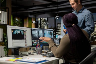 Modern teknoloji ve kurgu yazılımlarını yaratıcı bir video projesi için kullanarak post prodüksiyonda video çekimleri düzenleyen çok ırklı videograflardan oluşan bir ekip. Çift monitörlü modern çalışma alanı.