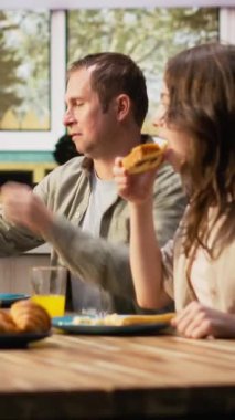 Dikey Video Ailesi mutfakta kahvaltı servisi yapıyor ve portakal suyu dolduruyor. Yumurta ve pastanın tadını birlikte çıkarıyorlar. Sabah rutini, hafta sonu yemekte paylaşılan neşe ve sevgiyle dolu. Kamera B.